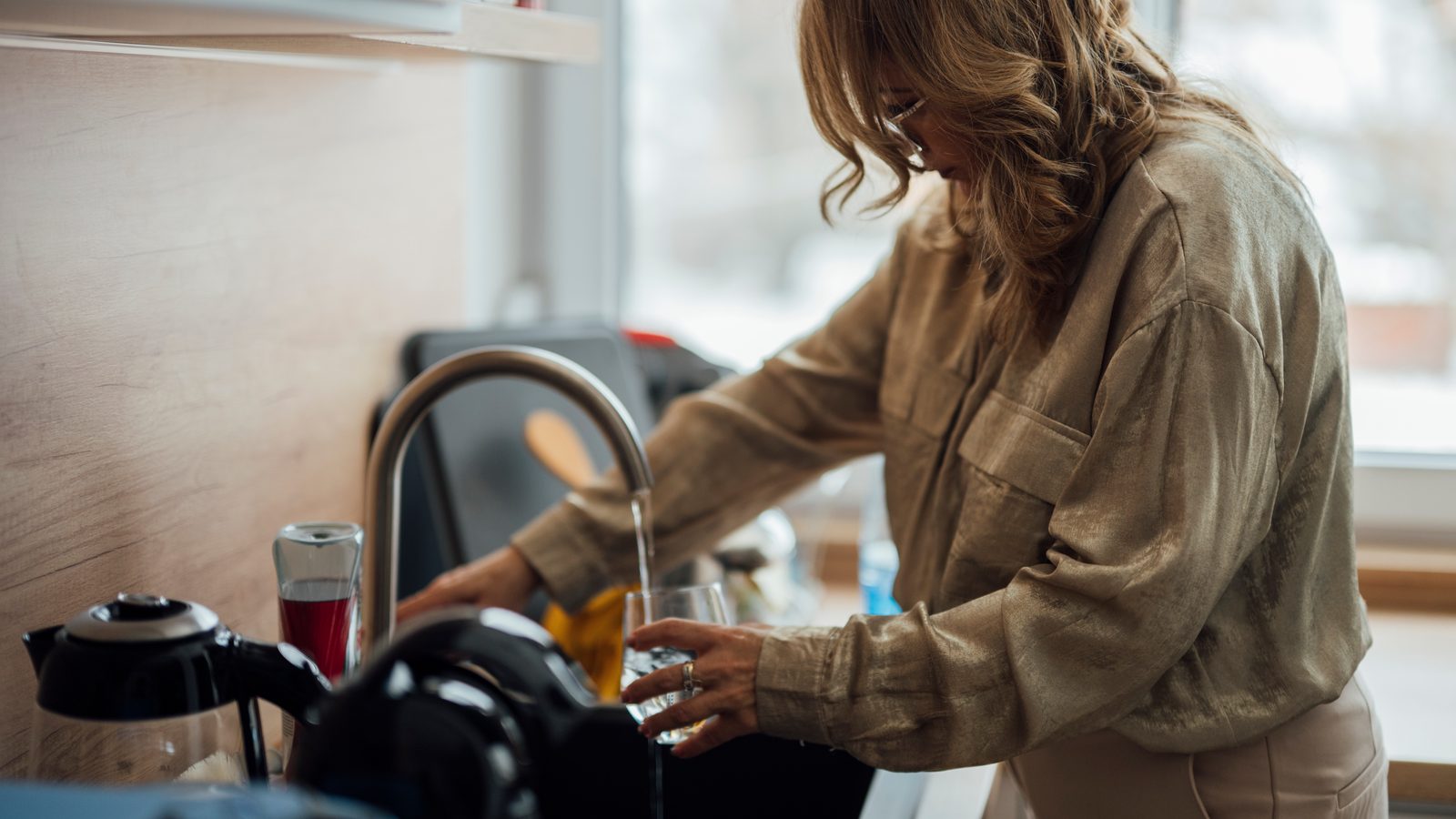 A clean blender jug and brush drying by a sink