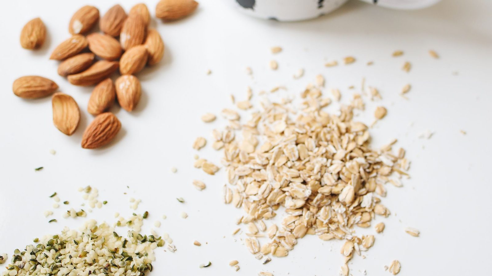 Measuring cups of almonds, oats, cashews and soybeans on a counter