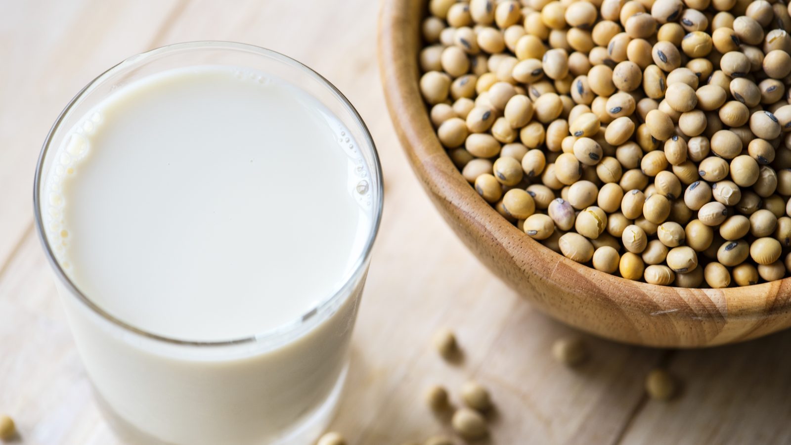 A glass of soy milk beside a bowl of dried soybeans