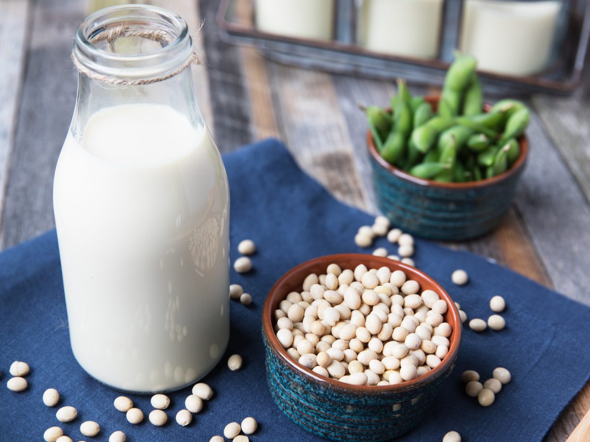 A glass of soy milk beside a bowl of soybeans
