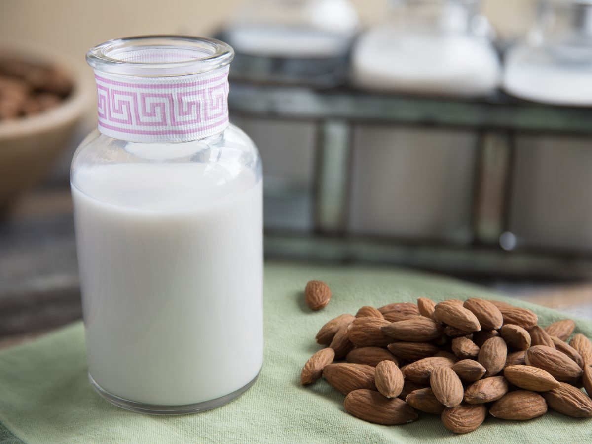 A bottle of homemade almond milk beside a bowl of almonds